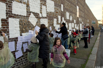 Groupe d'enfants et de parents décorant un mur de la ville