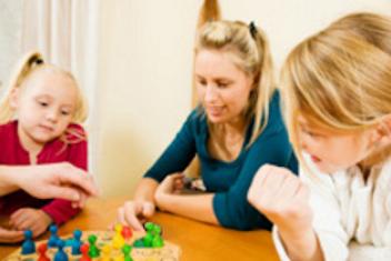 Une adulte et deux enfants jouant à un jeu de société