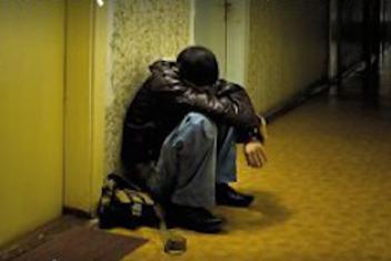 Une personne accroupie devant une porte