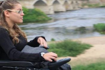 Jeune fille se deplaçant sur son fauteuil roulant au bord d'un fleuve