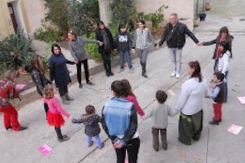 Des enfants et des adultes en ronde dans une cour