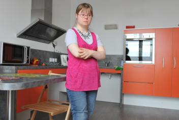 Une résidente dans sa cuisine, debout face à l'objectif