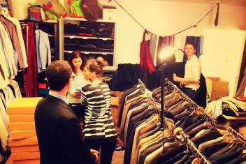 Dans un entrepôt, plusieurs personnes sont au milieu en train de ranger les vêtements recueillis.