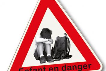 Dans un panneau "danger" un jeune garçon est assis en boule, la tête cachée dans ses bras sur ses genoux, son sac à dos à côté de lui. Sur le bas du panneau est écrit "enfant en danger"
