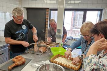 4 personnes âgées cuisinent ensemble autour d'un plan de travail. 