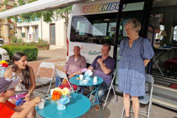 Des personnes attablées devant le bus, sous un auvent.