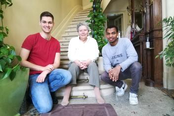 Deux jeunes et une personne âgée assis sur les marches d'un escalier